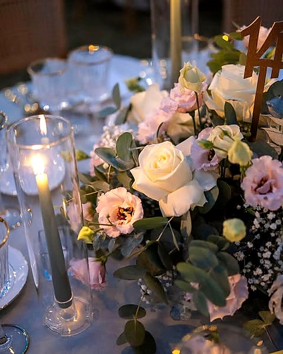 Rose bianche e lisianthus rosa su tavolo da cerimonia a lume di candela